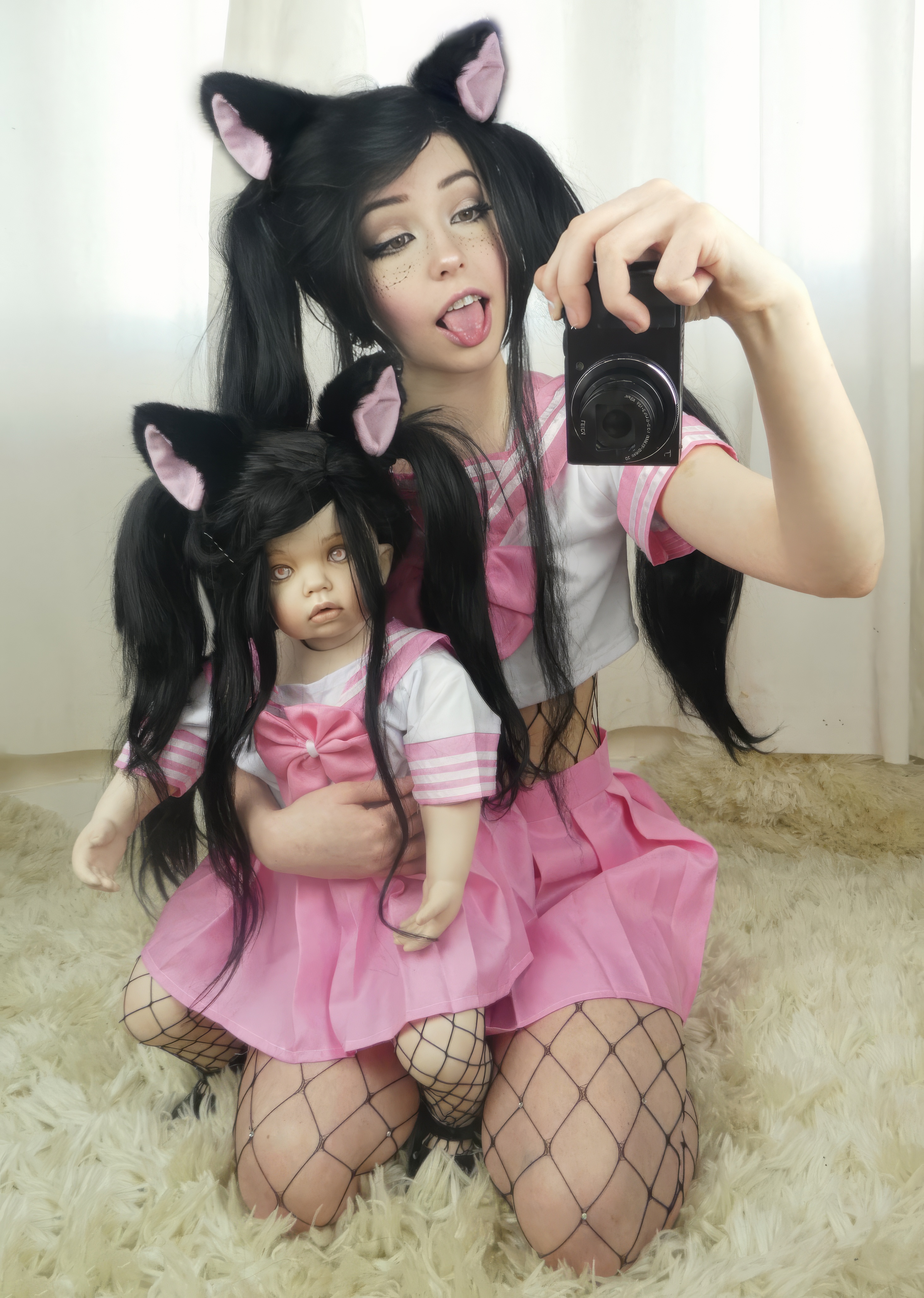Belle Delphine in pink wig and cat ears, surrounded by plushies, holding a shotgun across her lap — the visual language of her game-over-coded aesthetic.